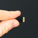 Male hand holding Micro SD card on black background.